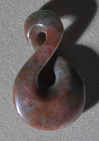 Carved pendant bead from blue-green colored jade.