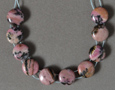 Pink and black rhodonite coin beads with veins.