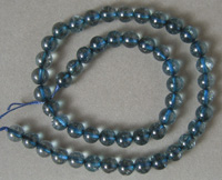 Strand of round beads from light blue tourmaline colored man made material.