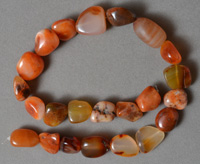 Mixed carnelian nugget beads on strand.